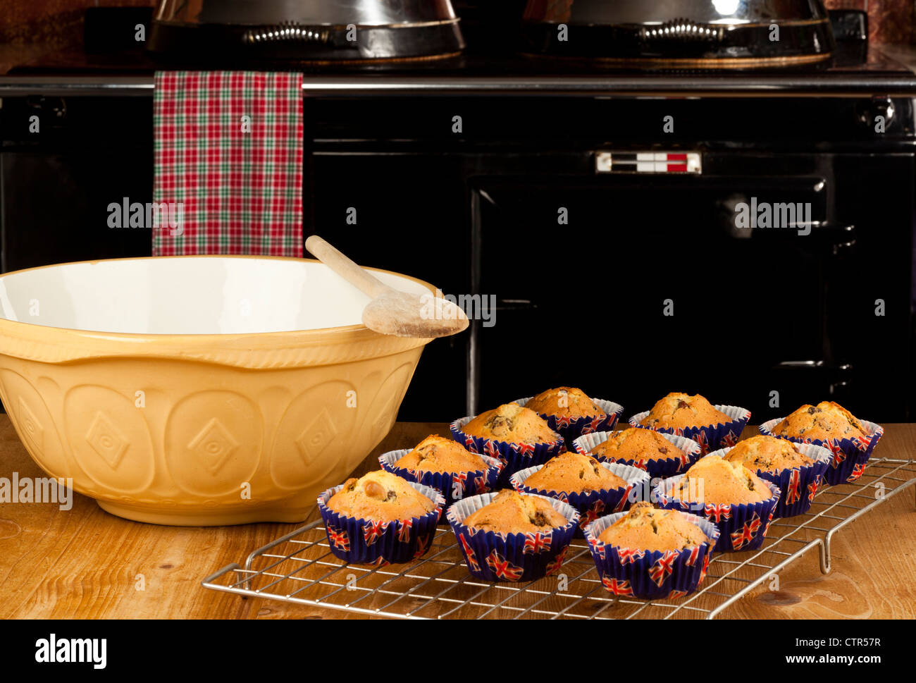 A dozen currant buns cooling on a kitchen table with a cooking range in the background Stock Photo