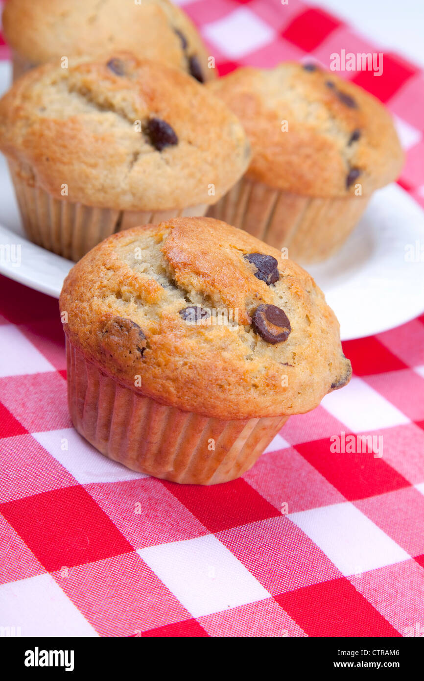 Homemade chocolate chip muffins on red gingham. Stock Photo