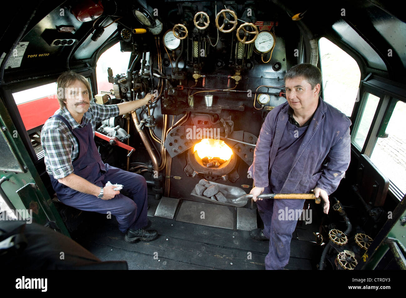 Train driver and fireman in the cab  of Southern Railway Steam Locomotive 'West Country' Class Pacific 4-6-2 Number 34028 'Eddystone' on the preserved Swanage Railway in Dorset UK Stock Photo