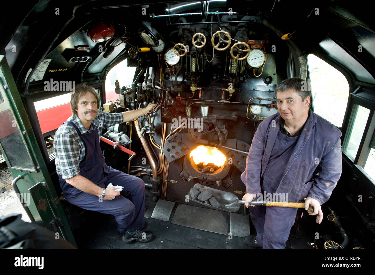 Train driver and fireman in the cab  of Southern Railway Steam Locomotive 'West Country' Class Pacific 4-6-2 Number 34028 'Eddystone' on the preserved Swanage Railway in Dorset UK Stock Photo