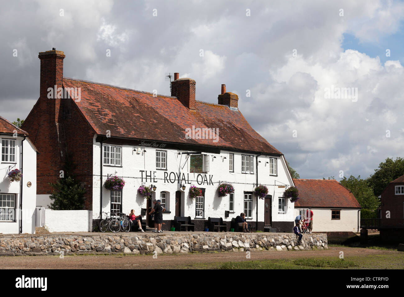 The Royal Oak Pub, a waterside pub at Langston on the south coast ar low tide with cycalists resting outside Stock Photo