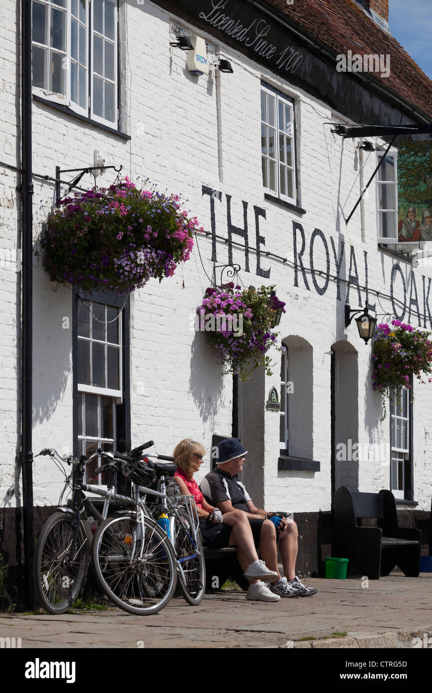 Cyclistics sat resting on a bench in the sunshine outside the Royal Oak Pub at Langston Stock Photo