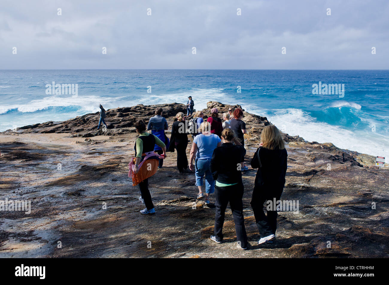 A group of women walking out to a rocky headland on North Stradbroke Island in Queensland Stock Photo