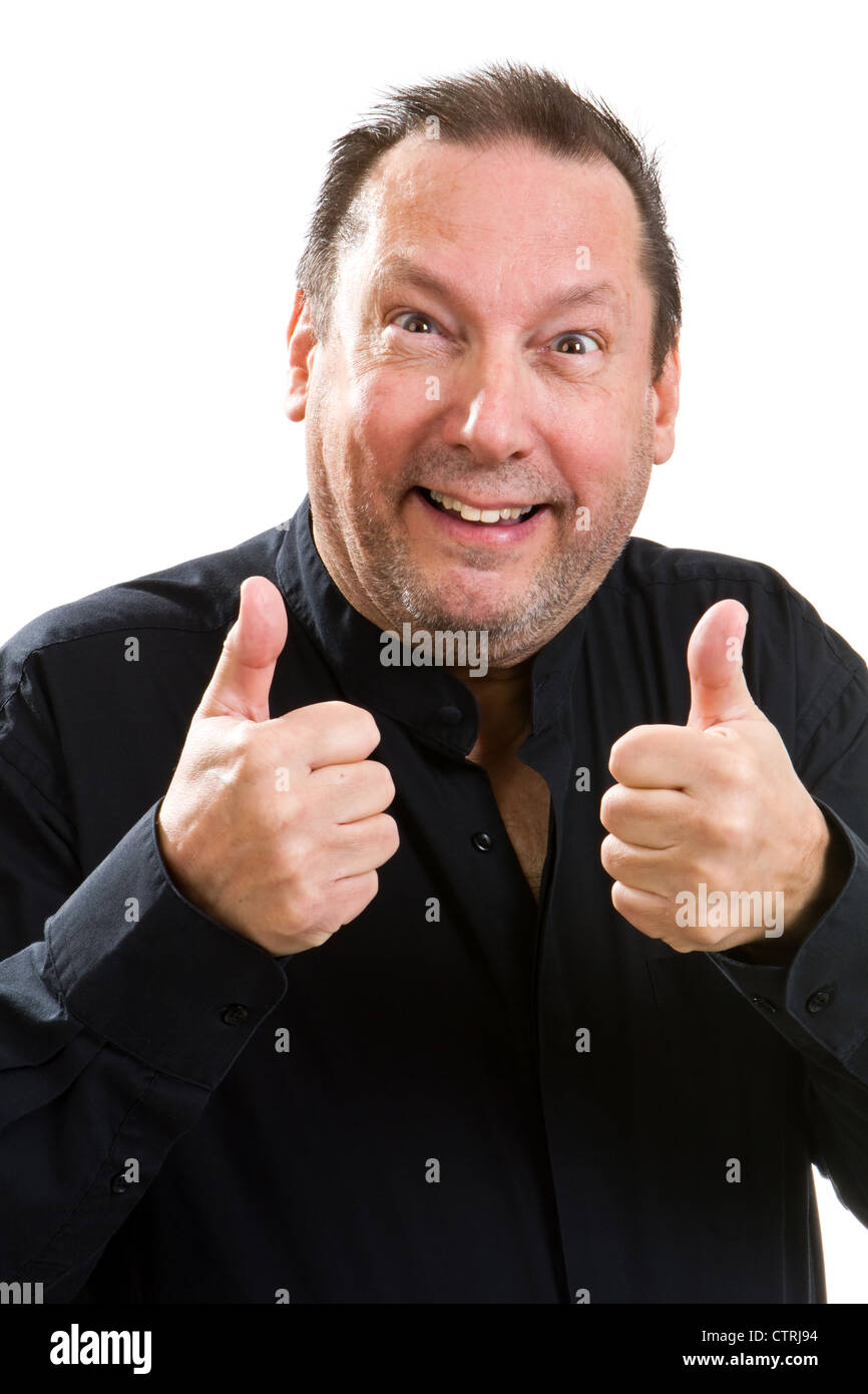 Elderly man with a silly expression on his face gestures with the thumbs up sign. Stock Photo