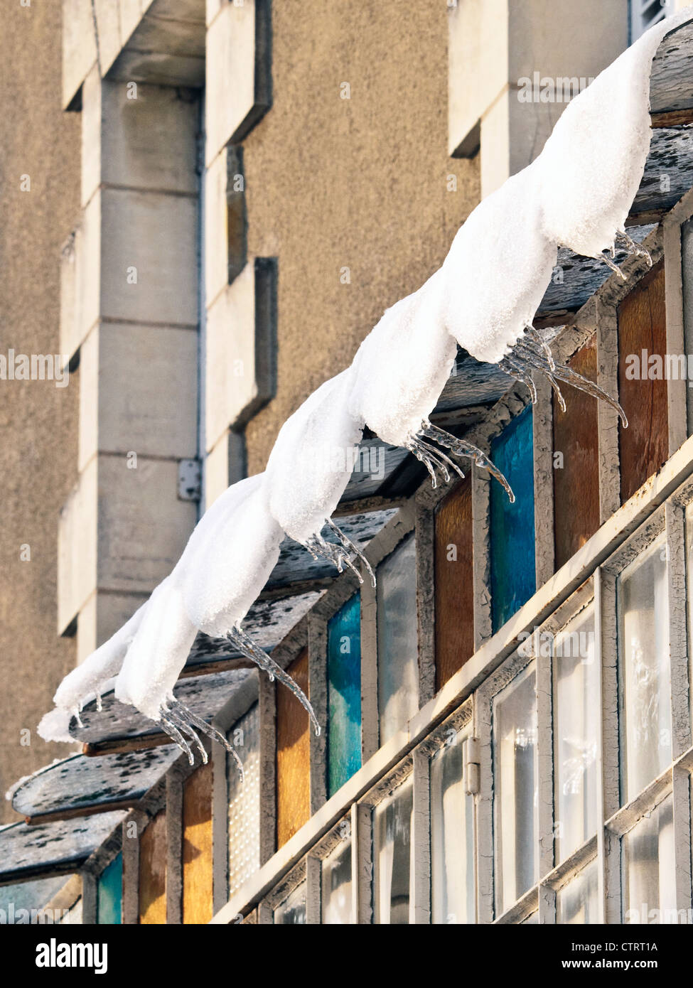 Curved icicles hanging from glass canopy - France. Stock Photo