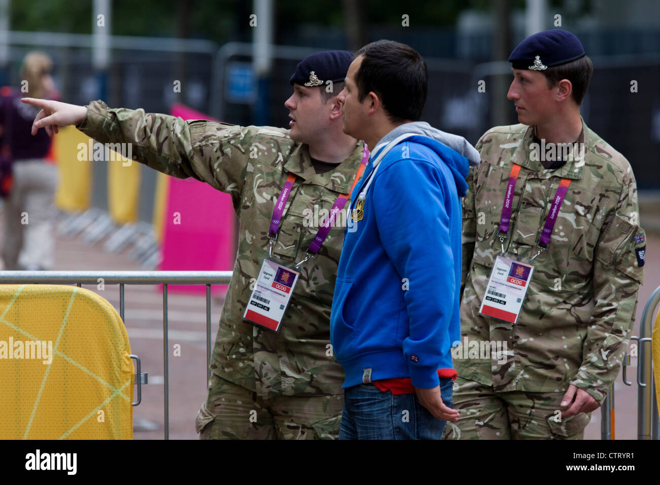 Soldiers of the Royal Artillery regiment in British army direct spectators while standing guard the entrance to the volleyball venue in central London next to the IOC rings logo on day 4 of the London 2012 Olympic Games. A further 1,200 military personnel are being deployed to help secure the 2012 Olympics in London following the failure by security contractor G4S to provide enough private guards. The extra personnel have been drafted in amid continuing fears that the private security contractor's handling of the £284m contract remains a risk to the Games. Stock Photo