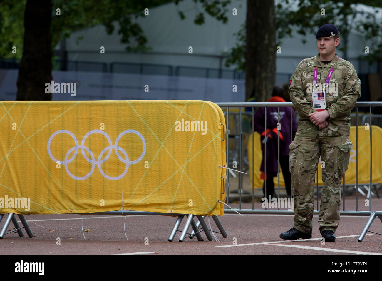 A soldier of the Royal Artillery regiment in the British army stand guarding the entrance to the volleyball venue in central London next to the IOC rings logo on day 4 of the London 2012 Olympic Games. A further 1,200 military personnel are being deployed to help secure the 2012 Olympics in London following the failure by security contractor G4S to provide enough private guards. The extra personnel have been drafted in amid continuing fears that the private security contractor's handling of the £284m contract remains a risk to the Games. Stock Photo