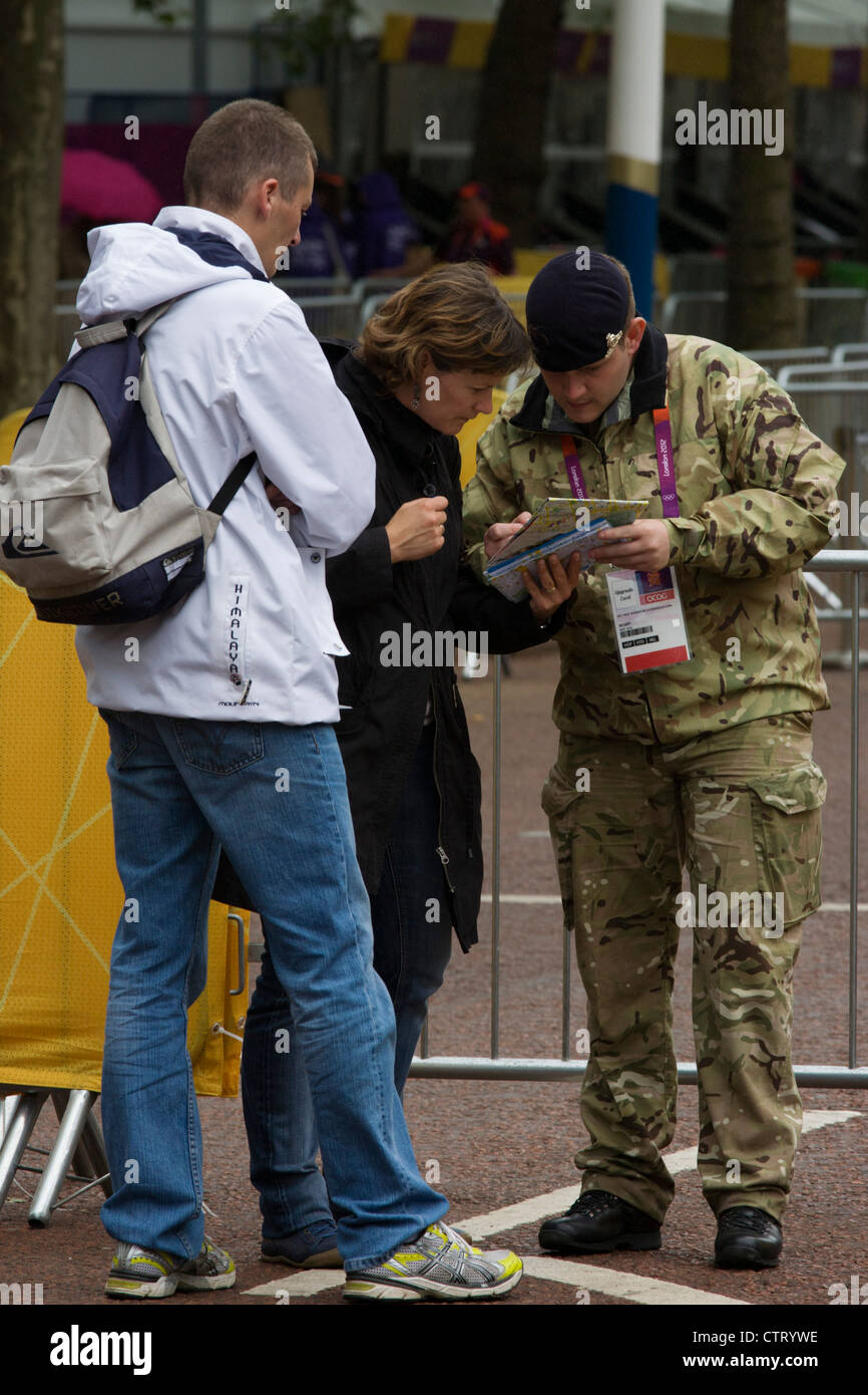 A soldier of the Royal Artillery regiment in the British army helps tourists while standing guard the entrance to the volleyball venue in central London next to the IOC rings logo on day 4 of the London 2012 Olympic Games. A further 1,200 military personnel are being deployed to help secure the 2012 Olympics in London following the failure by security contractor G4S to provide enough private guards. The extra personnel have been drafted in amid continuing fears that the private security contractor's handling of the £284m contract remains a risk to the Games. Stock Photo