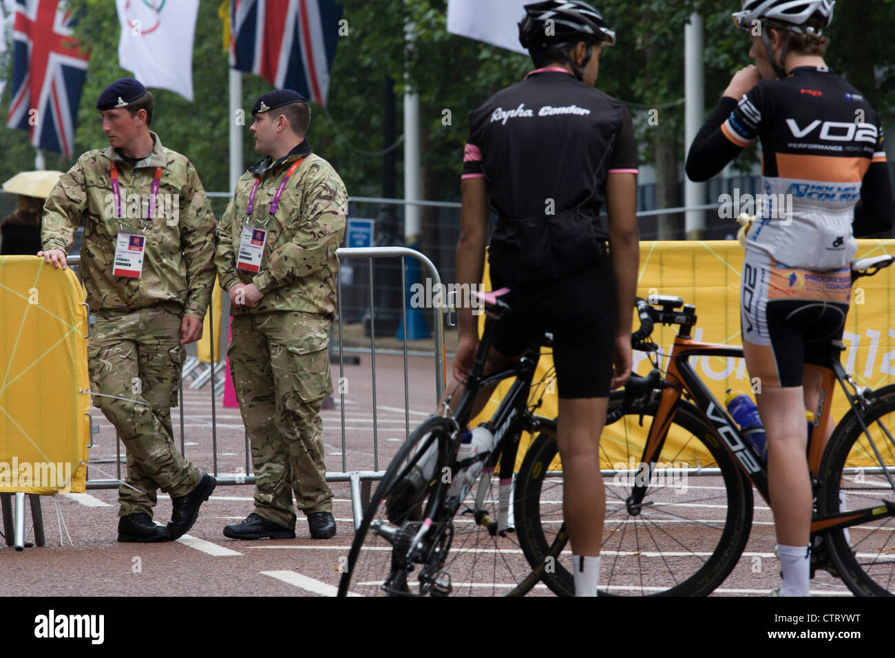 Cyclists with soldiers the Royal Artillery regiment in the British army stand guarding the entrance to the volleyball venue in central London next to the IOC rings logo on day 4 of the London 2012 Olympic Games. A further 1,200 military personnel are being deployed to help secure the 2012 Olympics in London following the failure by security contractor G4S to provide enough private guards. The extra personnel have been drafted in amid continuing fears that the private security contractor's handling of the £284m contract remains a risk to the Games. Stock Photo