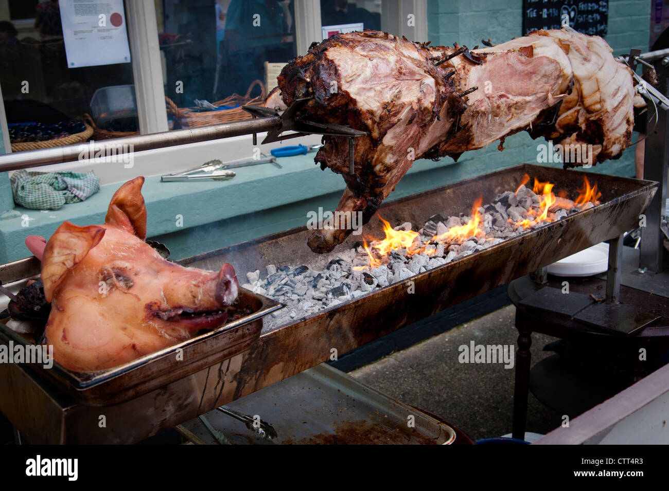 Hog spit roast on a barbecue with a pig's head in the foreground Stock Photo
