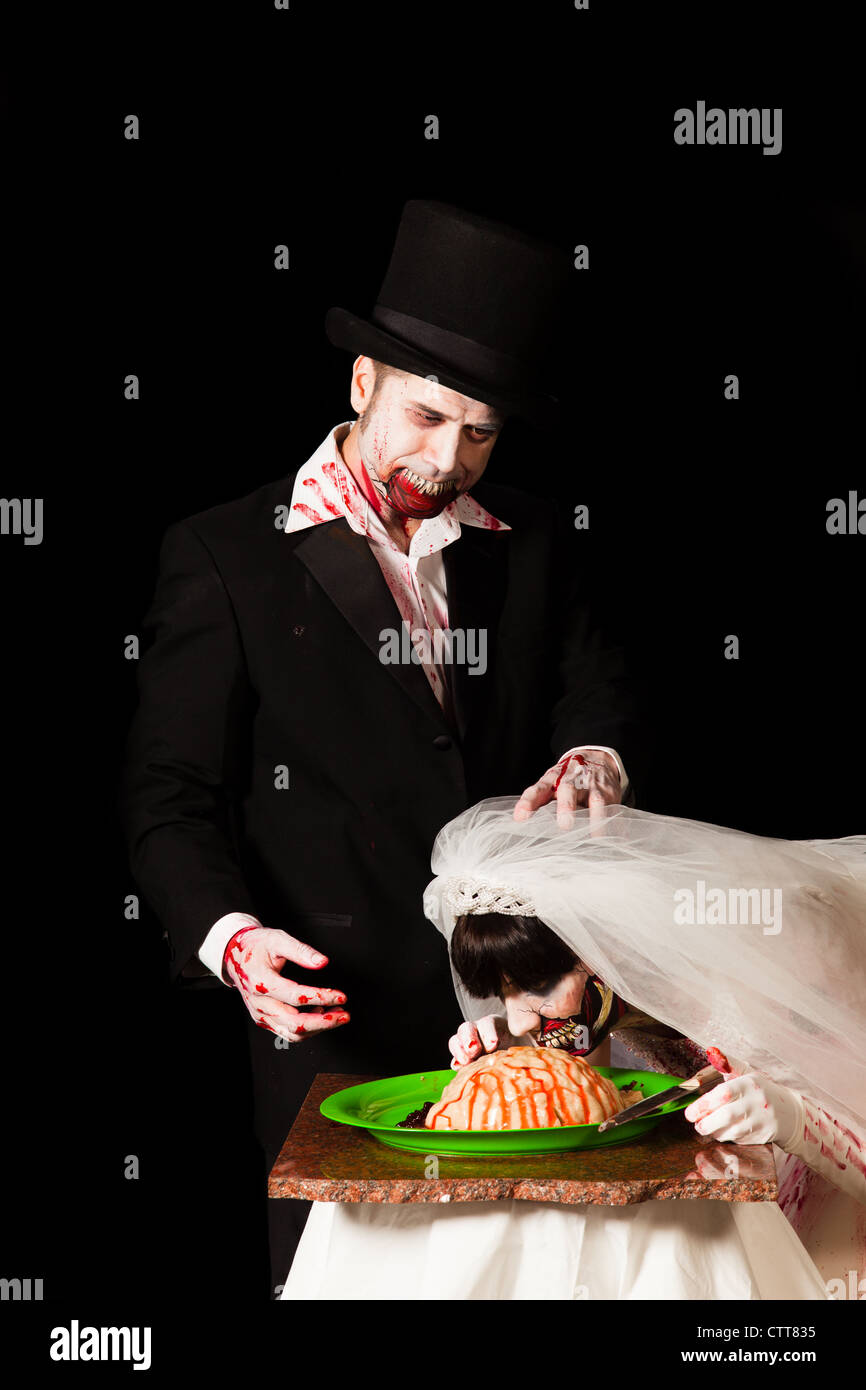 A zombie groom jokingly shoves his brides face into a platter of brains Stock Photo