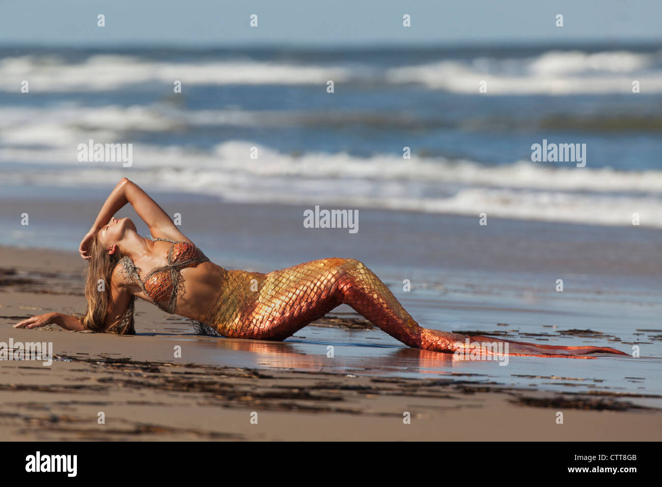 Young mermaid laying in the sand sunning herself in Virginia Beach, Virginia. Stock Photo