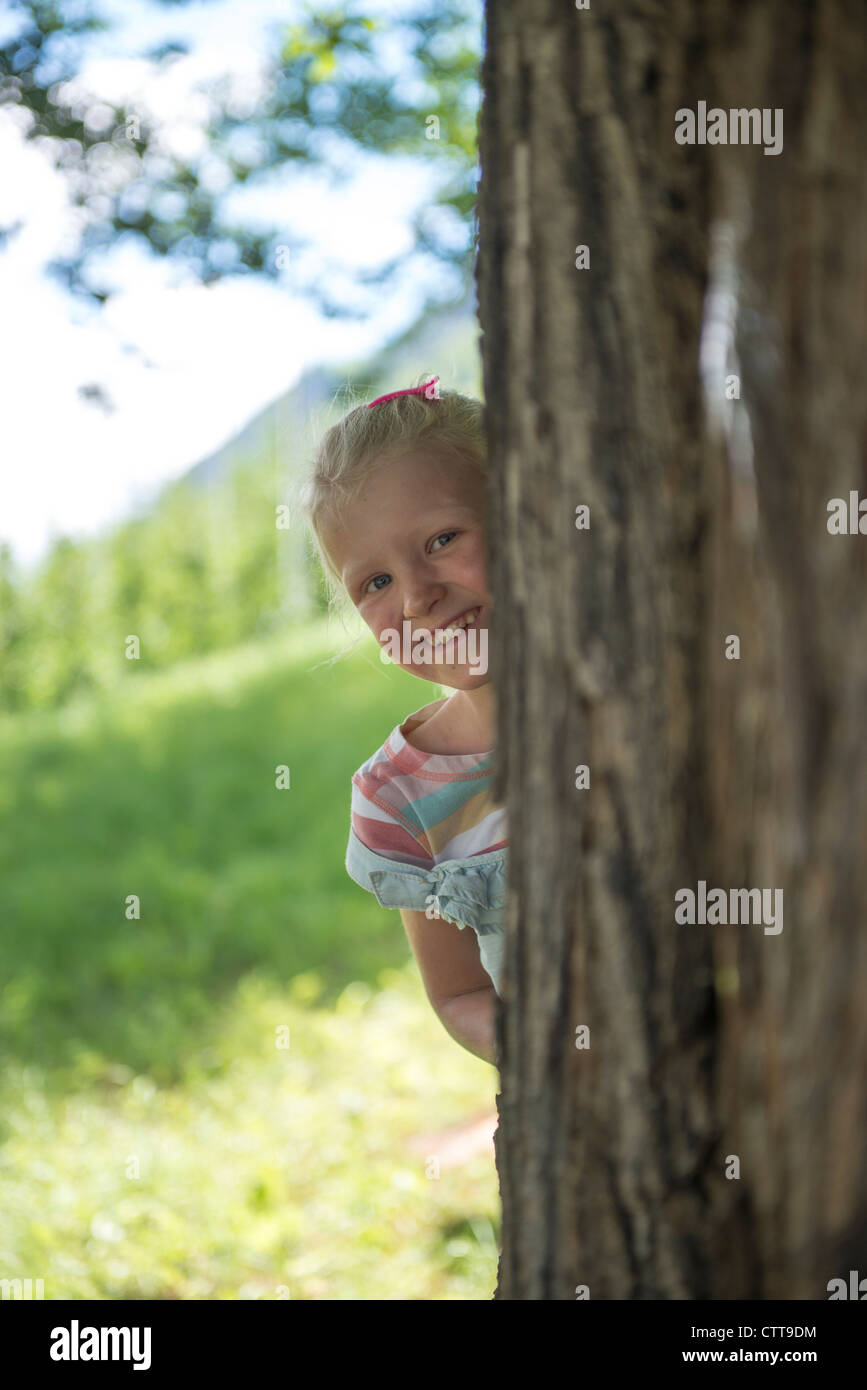 Girl looking out behind tree Mädchen schaut hinter Baum heraus Stock Photo