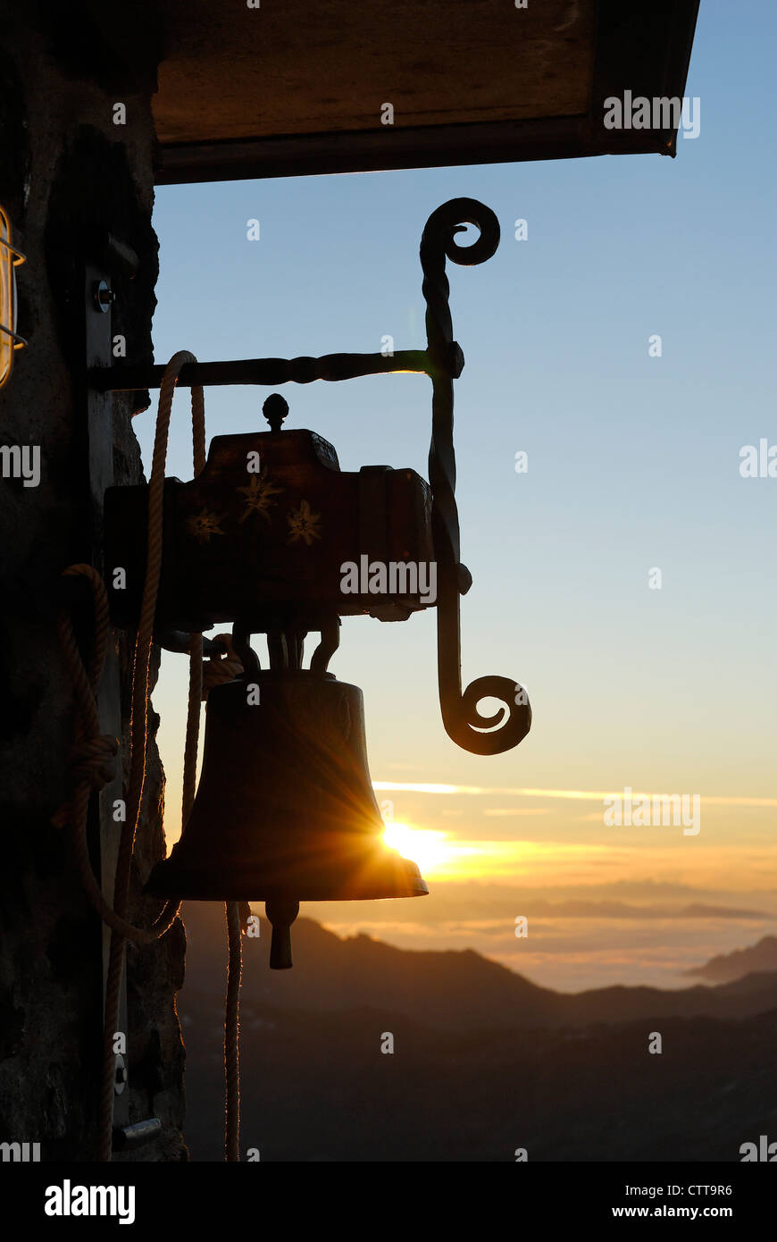 Glocke bei Schutzhaus bei Sonnenaufgang Bell on mountain shelter on sunrise Stock Photo