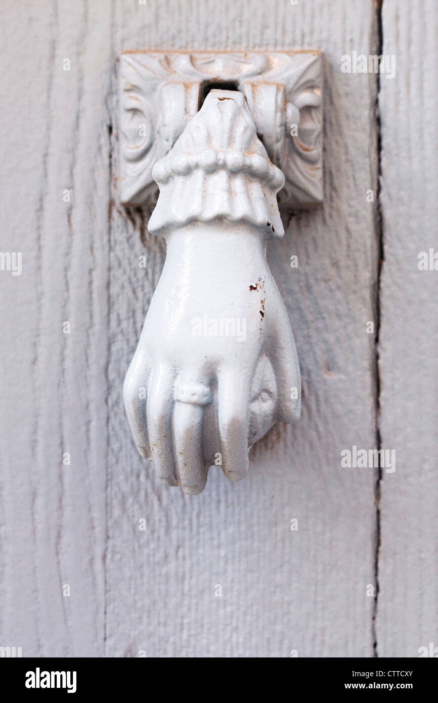 Hand door knocker on a white wooden door. Stock Photo