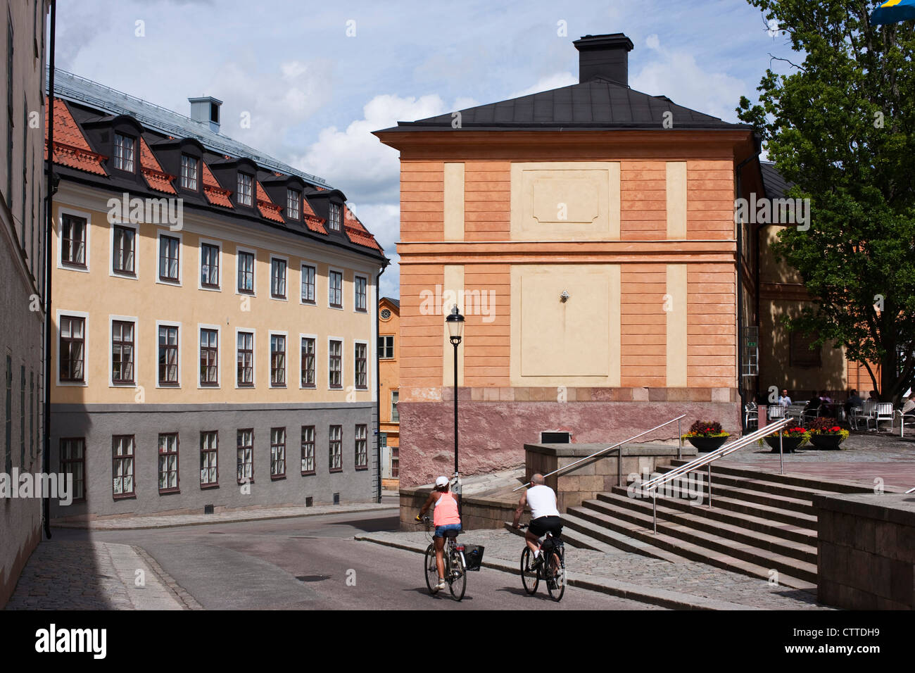A couple cycle through the streets of Uppsala's old town. Sweden. Stock Photo
