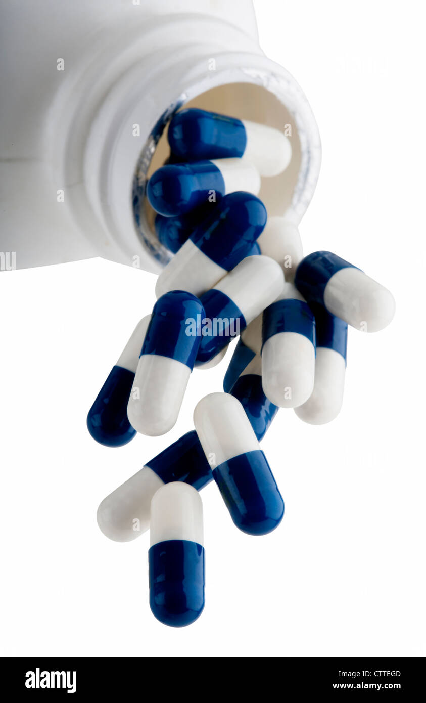 Blue and White capsules falling out of prescription bottle Stock Photo