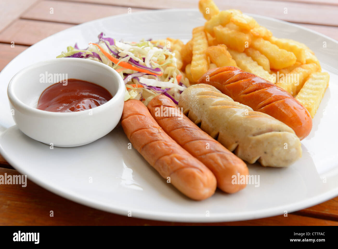 Mixed sausage served with french fried in the white dish put on the wood table Stock Photo