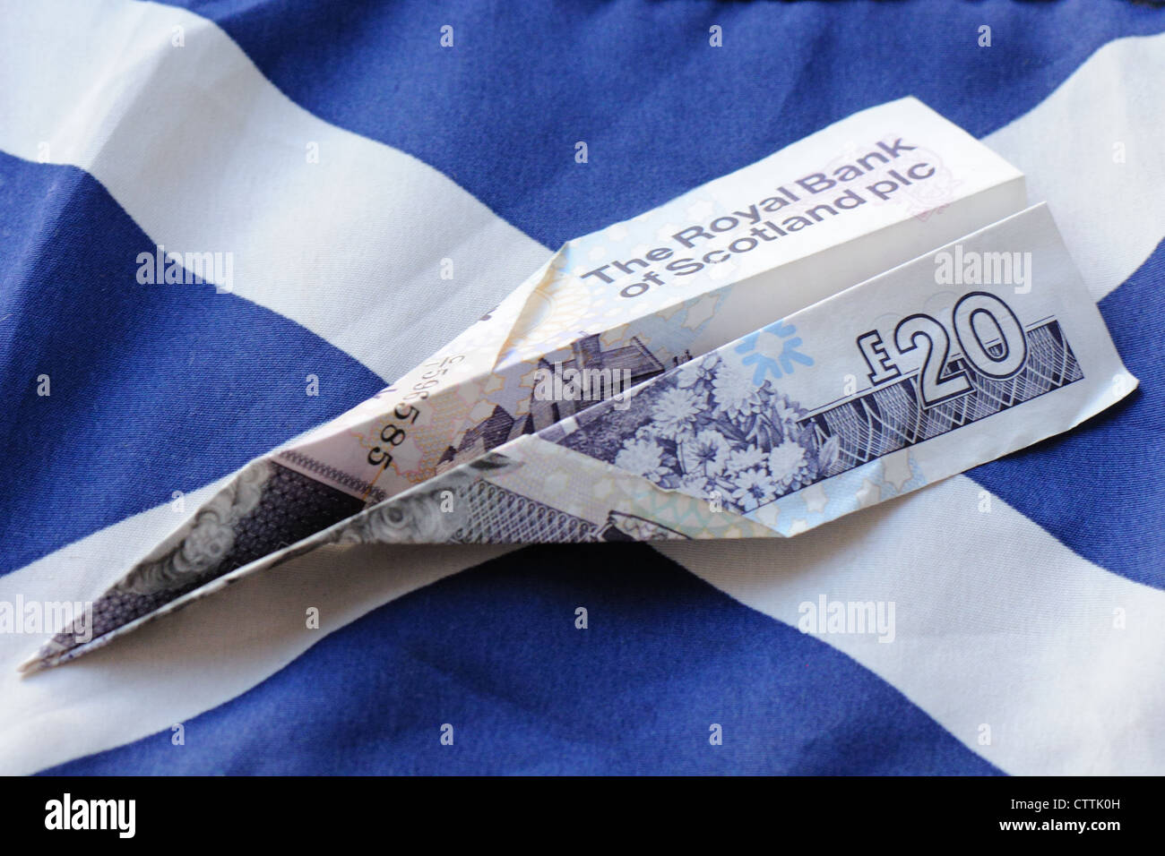 Royal bank of Scotland 20 pound note folded to make paper plane on Scottish flag Stock Photo