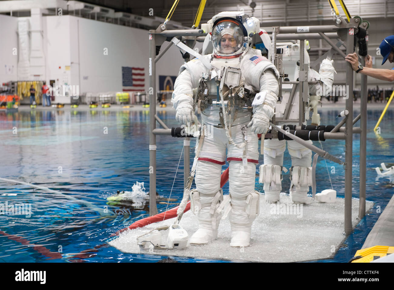 Attired in training versions of their Extravehicular Mobility Unit (EMU) spacesuits, NASA astronauts Rex Walheim and Sandy Magnus (partially obscured), both STS-135 mission specialists, are about to be submerged in the waters of the Neutral Buoyancy Laboratory (NBL) near NASA's Johnson Space Center. Divers are in the water to assist Walheim and Magnus in their rehearsal, which is intended to help prepare them for work on the exterior of the International Space Station. STS-135 is planned to be the final mission of the space shuttle program. Stock Photo