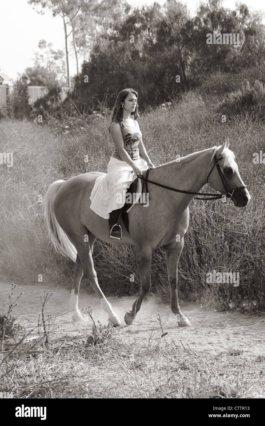 Attractive girl riding on horse in deserted rural location Stock Photo