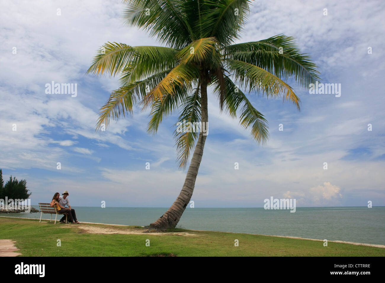 Couple sitting on a bench by the ocean Stock Photo - Alamy