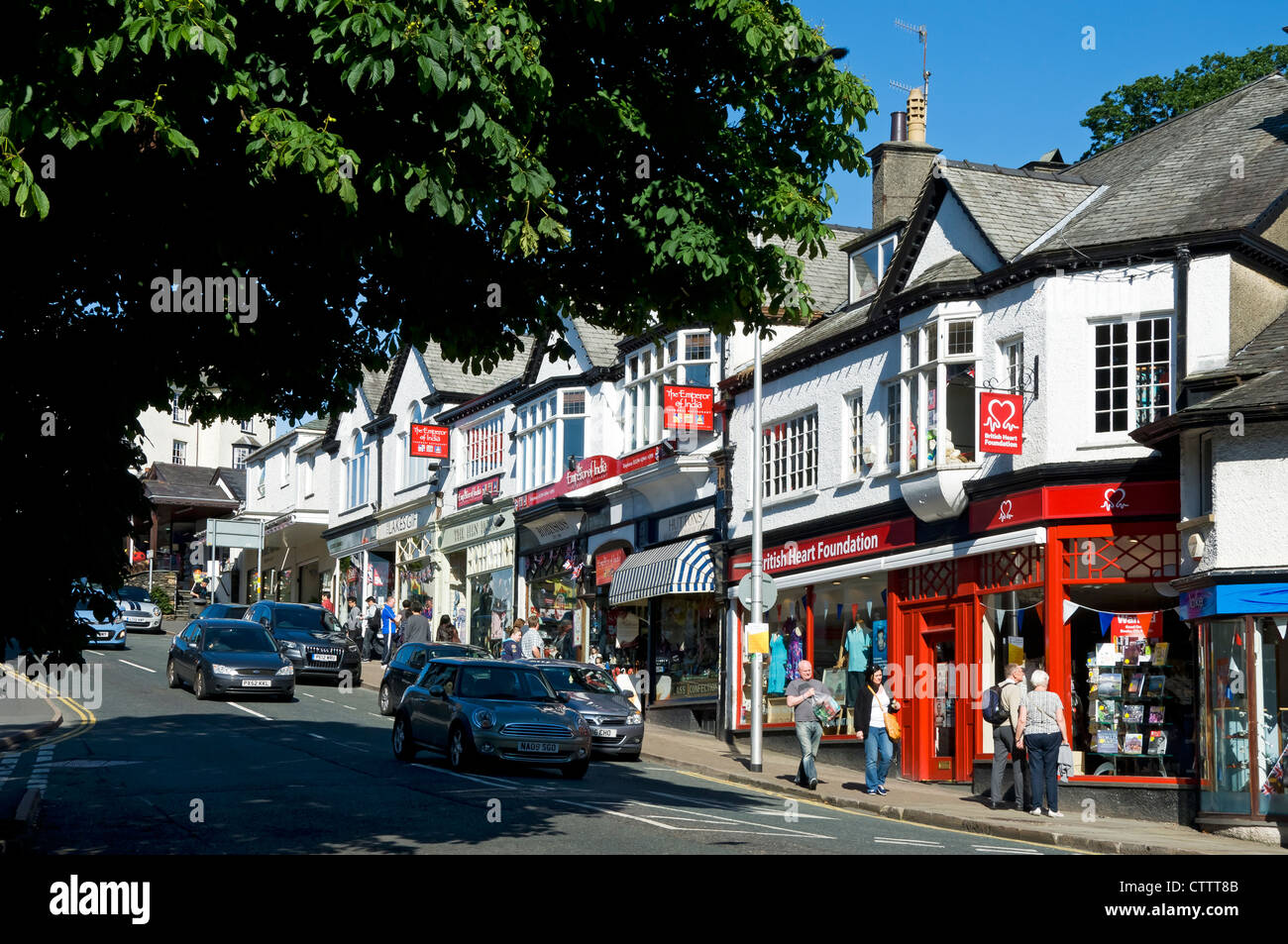 People visitors tourists walking by shops stores in the town centre in summer Bowness on Windermere  Cumbria England UK United Kingdom Great Britain Stock Photo