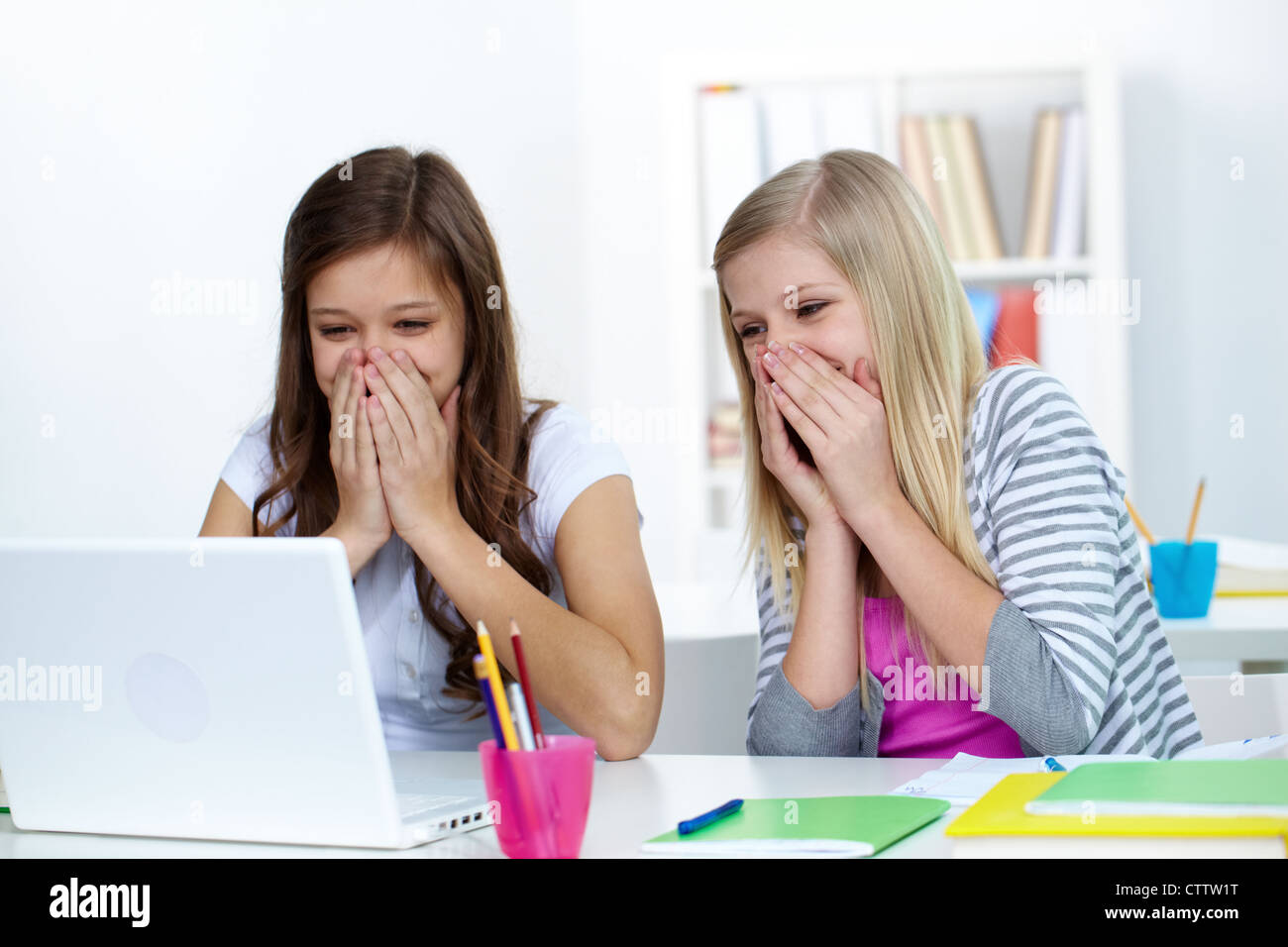 Two laughing girls looking at laptop screen in college Stock Photo Alamy