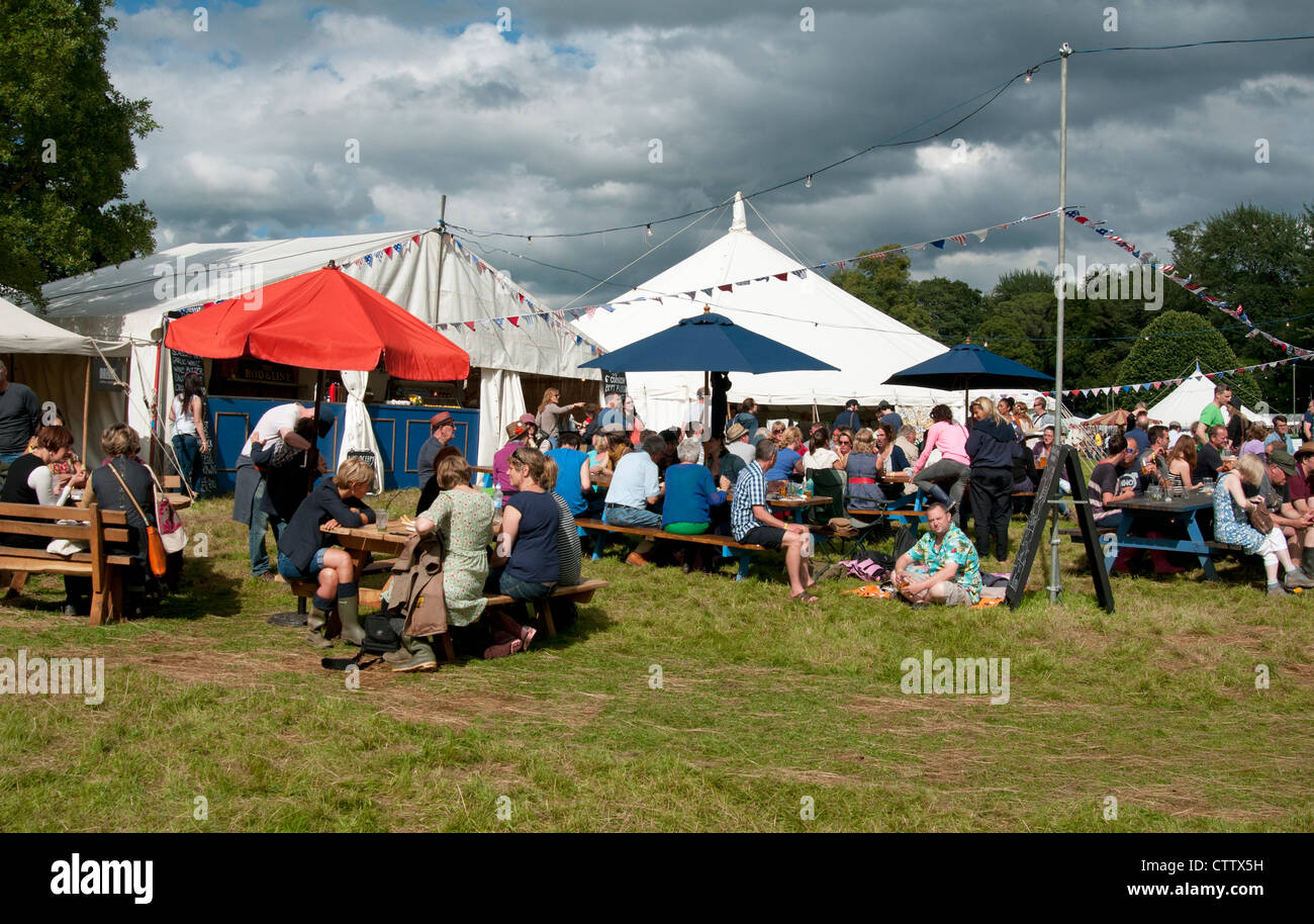 People drinking outside a tent with summer storm clouds in the sky at the Port Eliot literary festival St Germans Cornwall UK Stock Photo