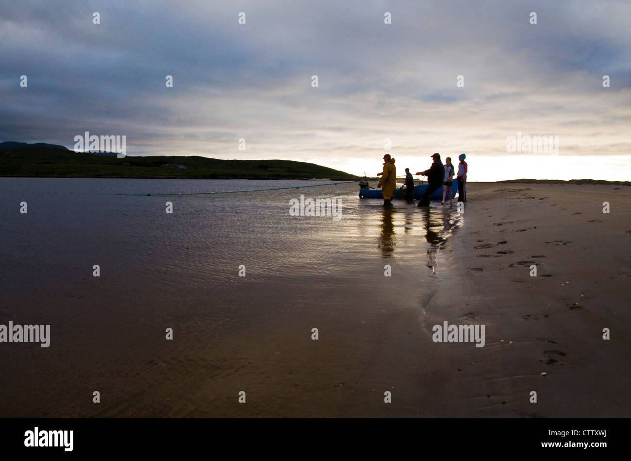 Draft net salmon fishing men haul in net watched by family on Donegal