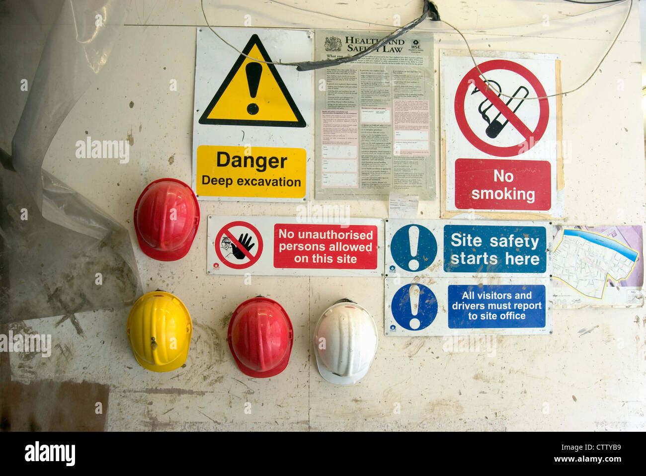 Hard hats hanging at an entrance of a site with safety regulation signs
