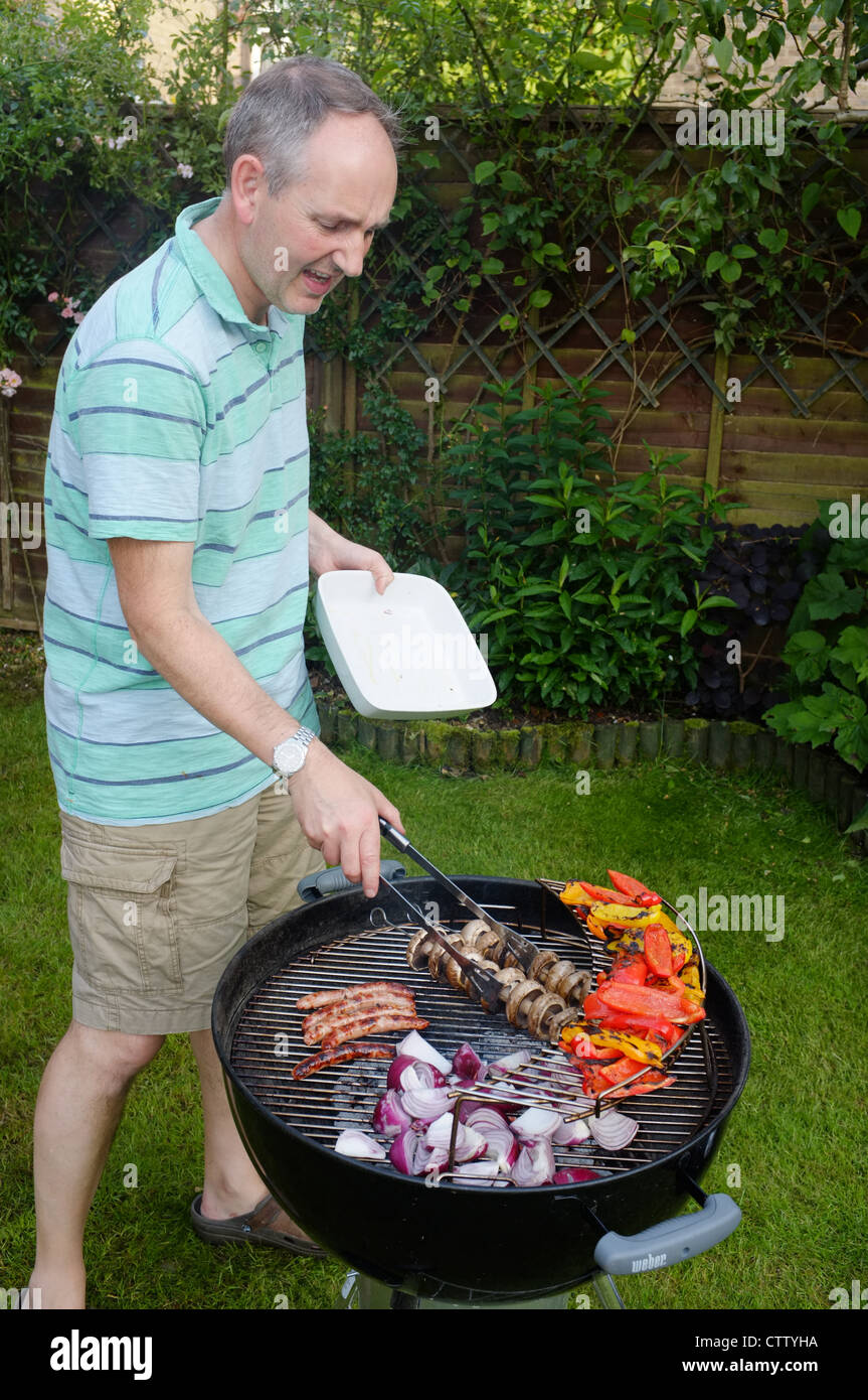 Man cooking fajitas on a barbecue in a garden in UK Stock Photo
