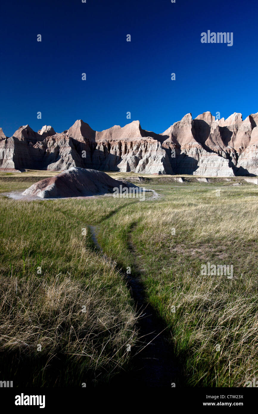 Hiking trail through grasslands leading to rock formations, Badlands