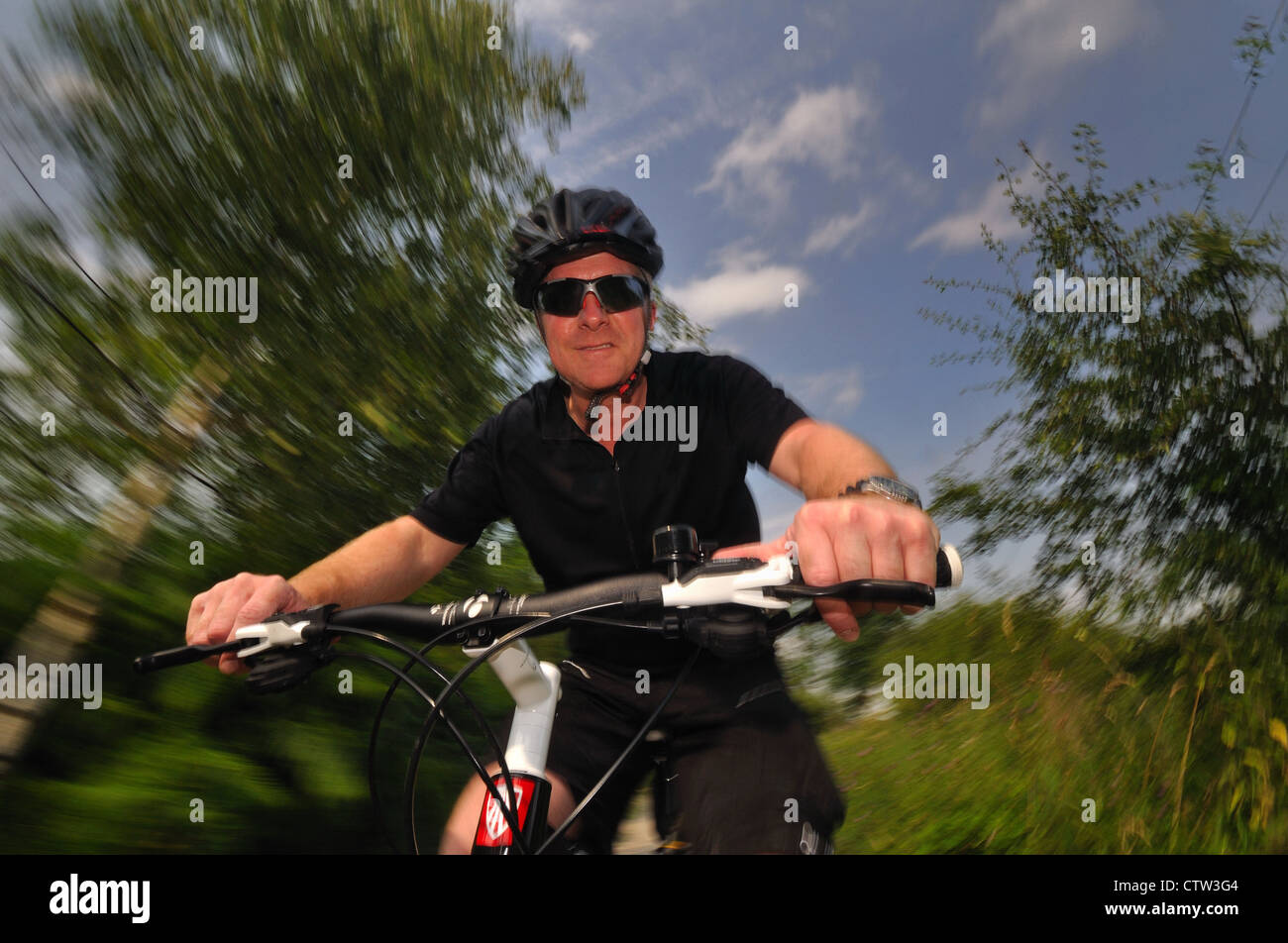 Middle aged man on a mountain bike with blue sky background, showing ...