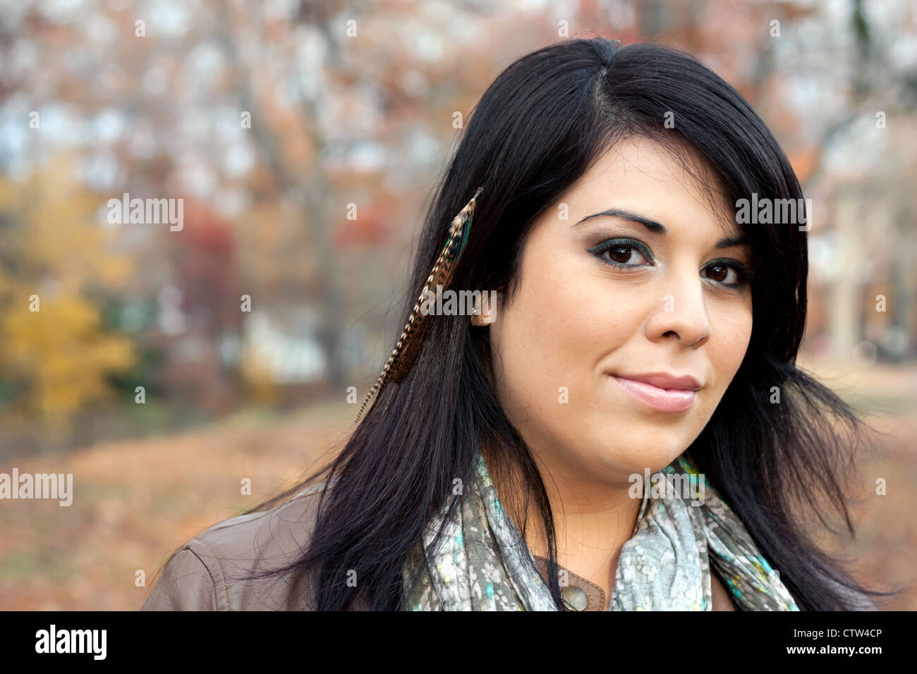 Beautiful young Hispanic woman wearing custom feather hair extensions in her black hair. Stock Photo