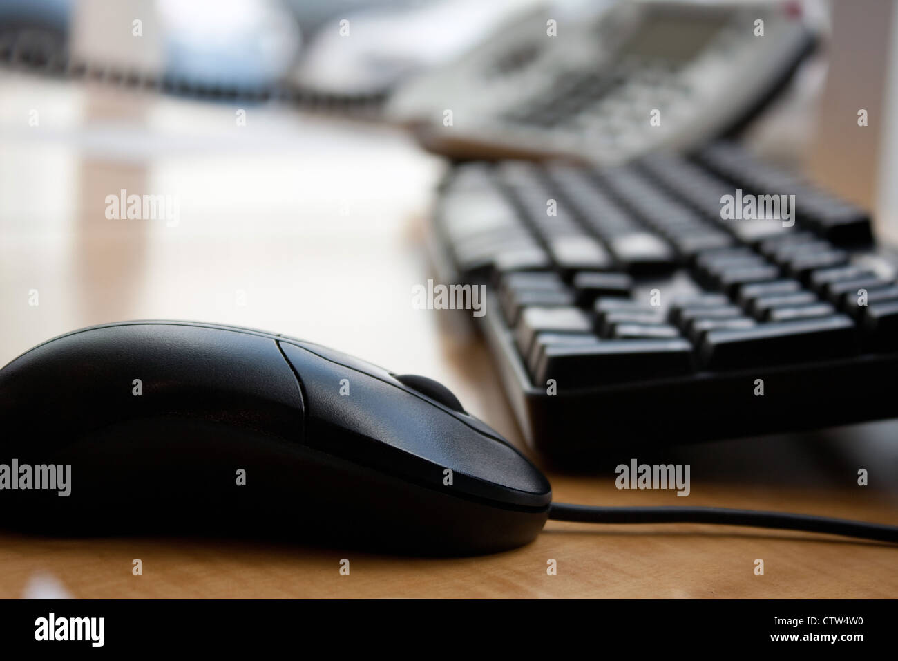 Close up of a modern office workplace desk setup with a computer mouse keyboard and phone. Shallow depth of field. Stock Photo