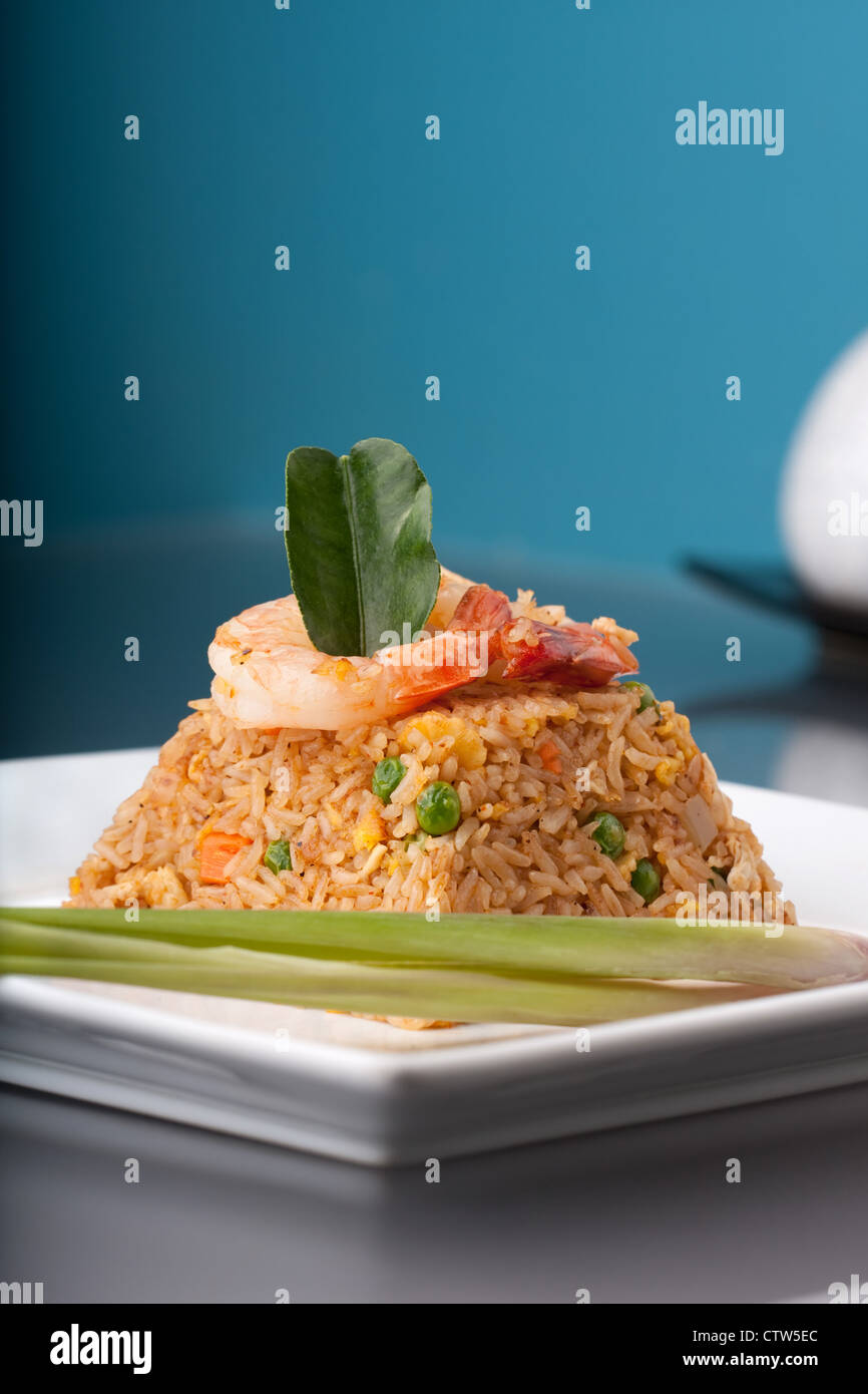 Thai style shrimp fried rice presented on a square white plate in the shape of a pyramid. Stock Photo