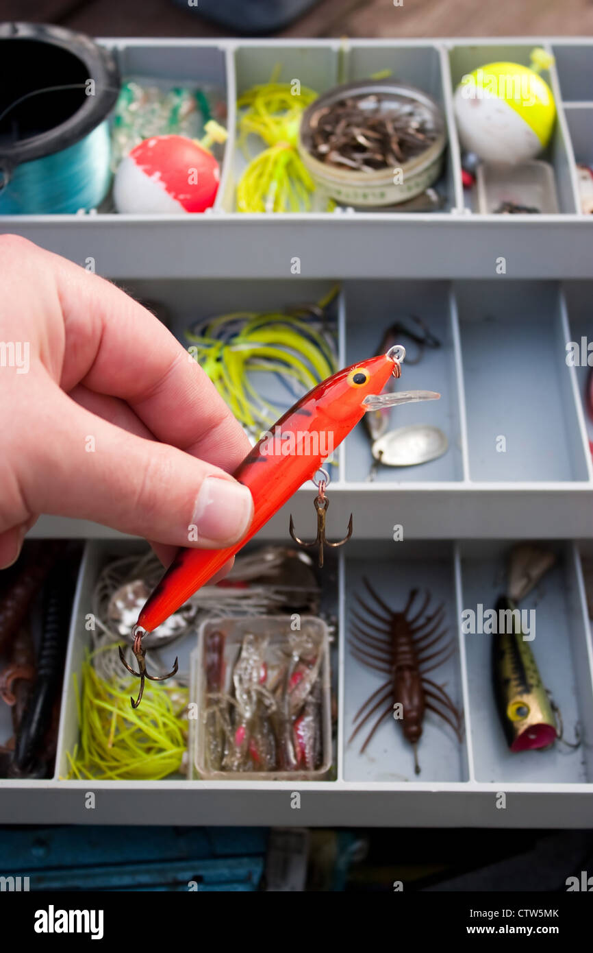 https://c8.alamy.com/comp/CTW5MK/a-fisherman-selects-the-right-lure-from-his-tackle-box-that-he-is-CTW5MK.jpg