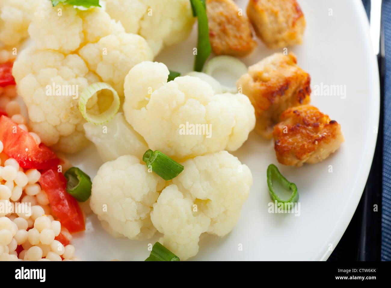 Couscous with tomatoes and fresh steamed cauliflower and meat substitute. Stock Photo