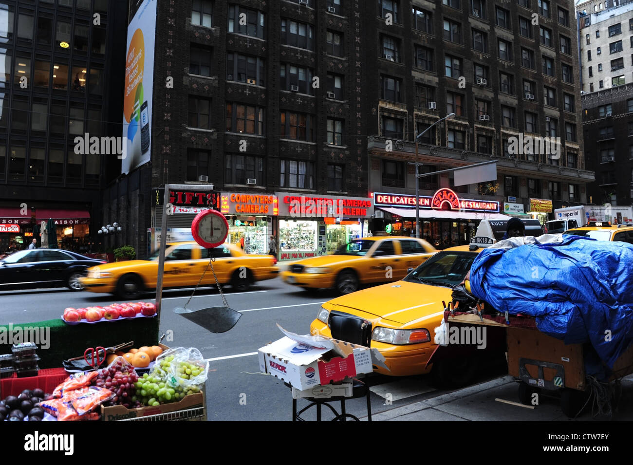 Morning view, towards red neon Stage Restaurant, sidewalk fruit stall, motion-blur yellow taxis, 7th Avenue, New York Stock Photo