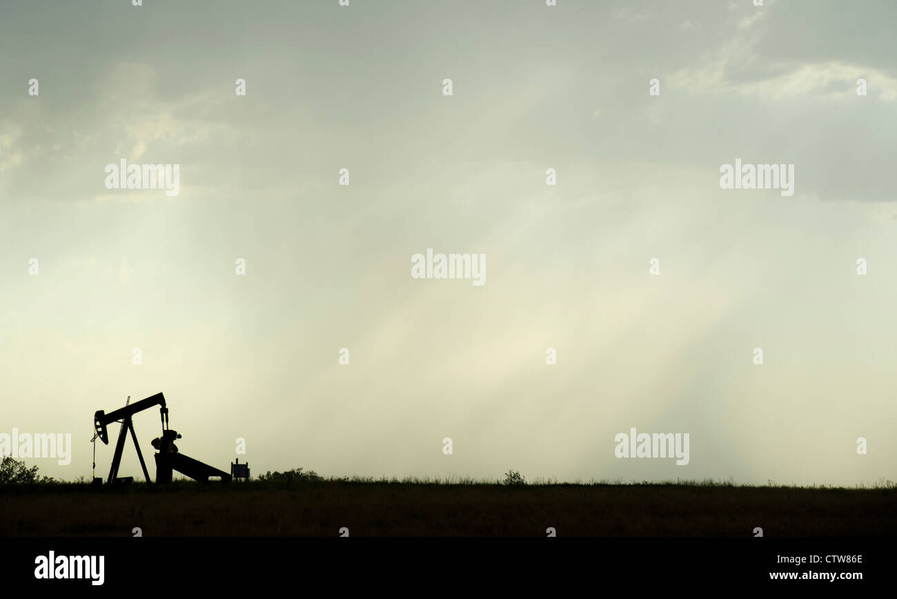 An oil derrick continues to pump during an afternoon thunderstorm near
