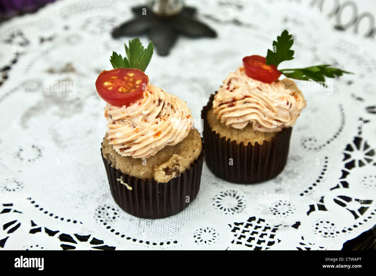 charming delicious mini cupcakes topped with strawberry whipped cream cherry tomato & a leaf displayed on paper doily Edmonds Stock Photo