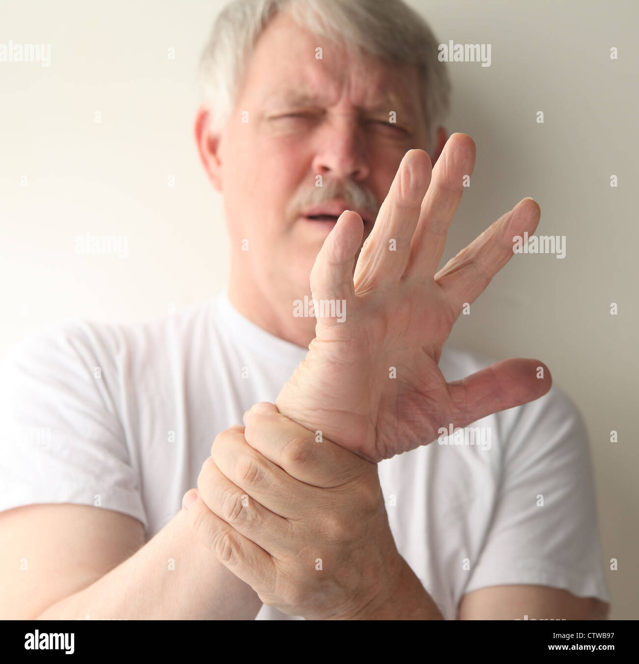 a senior man winces at the pain in his hand Stock Photo Alamy