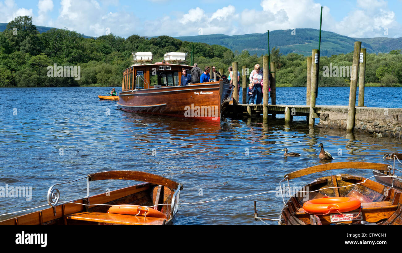 Tourists on a ferry with rowing boats in the foreground on Derwentwater, Keswick in the Lake District, Cumbria Stock Photo