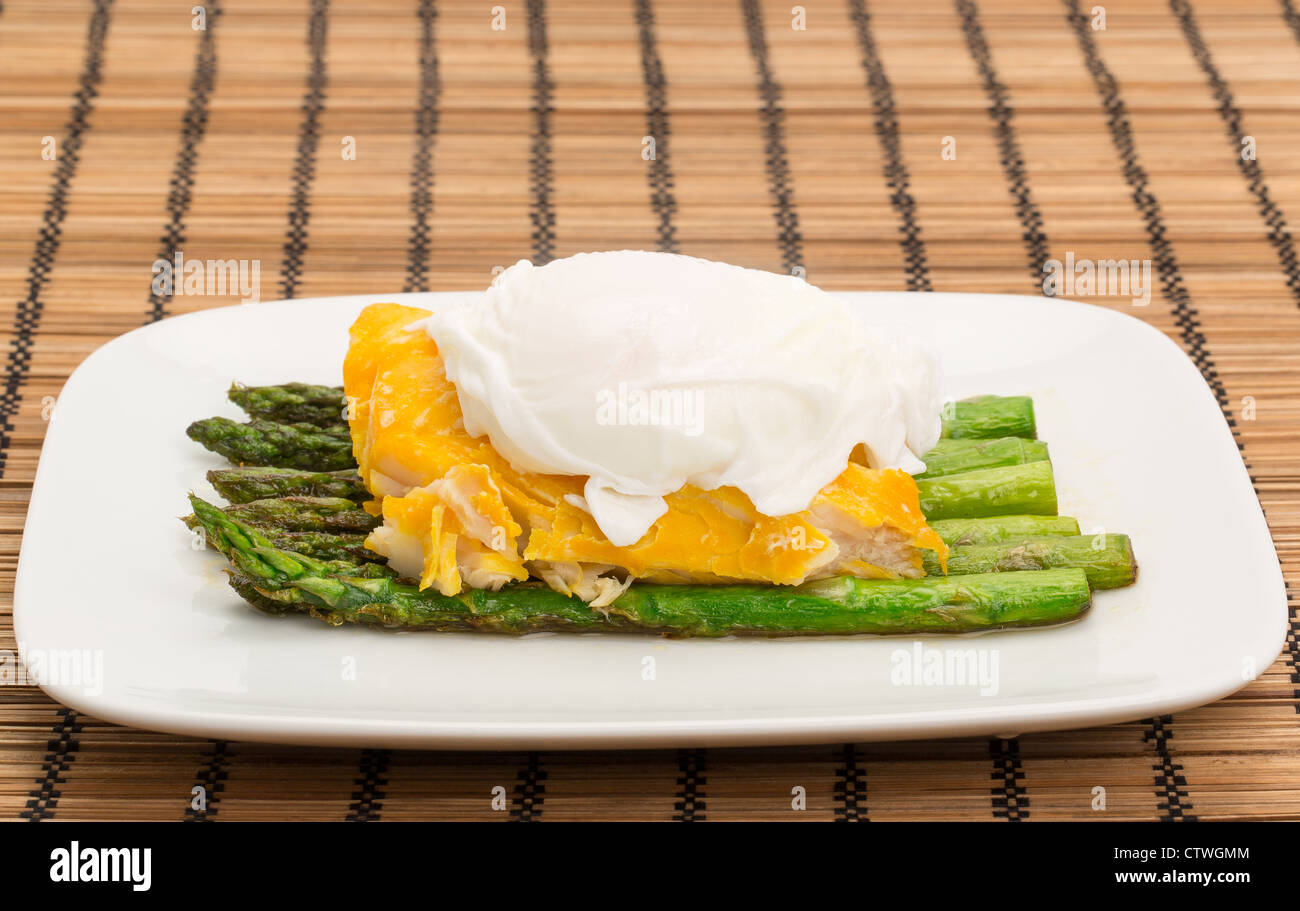 Smoked haddock, asparagus and a poached egg dinner arranged on a china plate Stock Photo