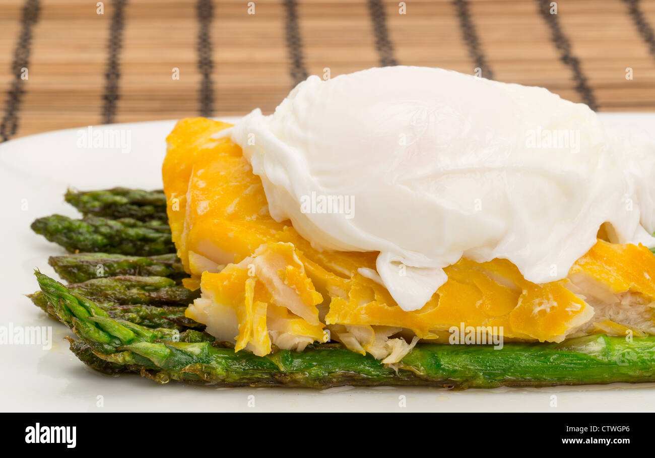 Close-up shot of a smoked haddock, asparagus and a poached egg dinner arranged on a china plate Stock Photo