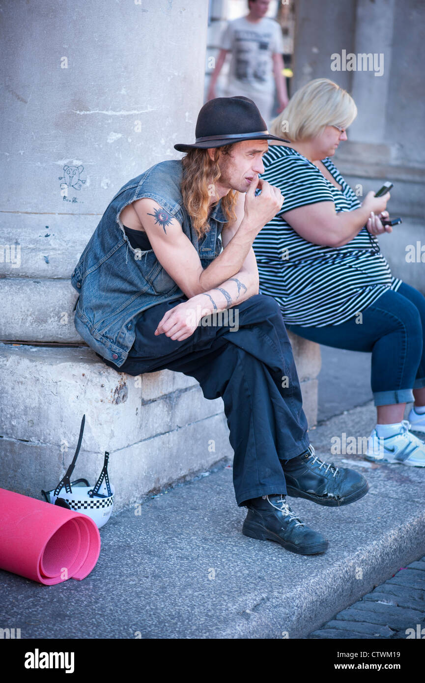 London Covent Gardens Market young man male denim jacket trilby long blond hair sideburns tattoos tats worn shoes string laces Stock Photo