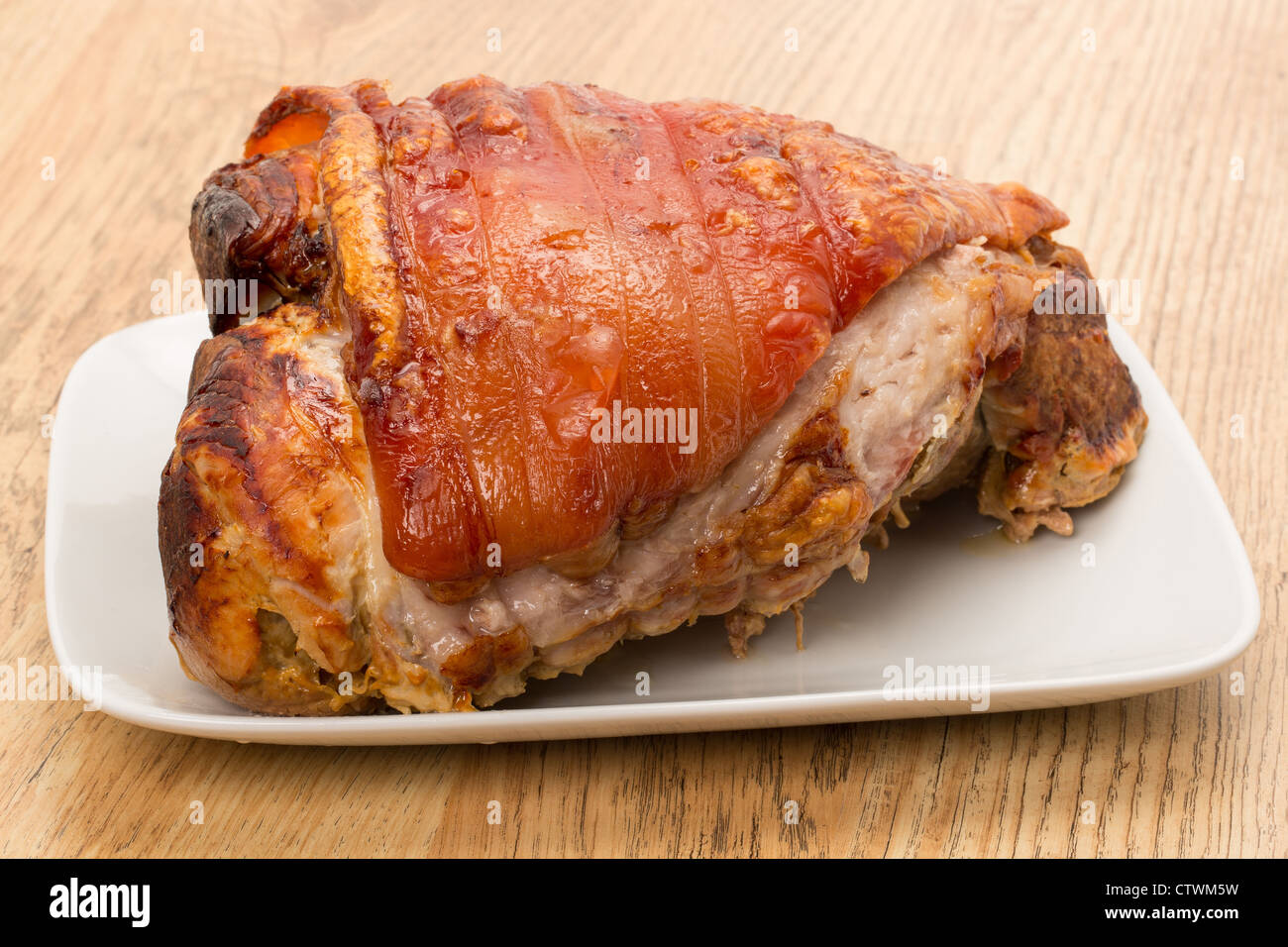 A roast pork joint on a white plate studio shot Stock Photo Alamy