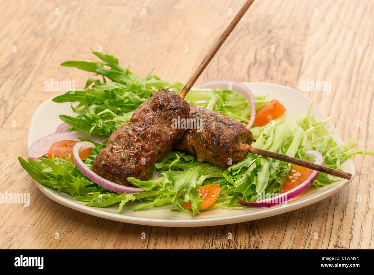 Beef shish kebabs or kofta with sweet chilli seasoning and parsley served  on a bed of salad - studio shot Stock Photo - Alamy