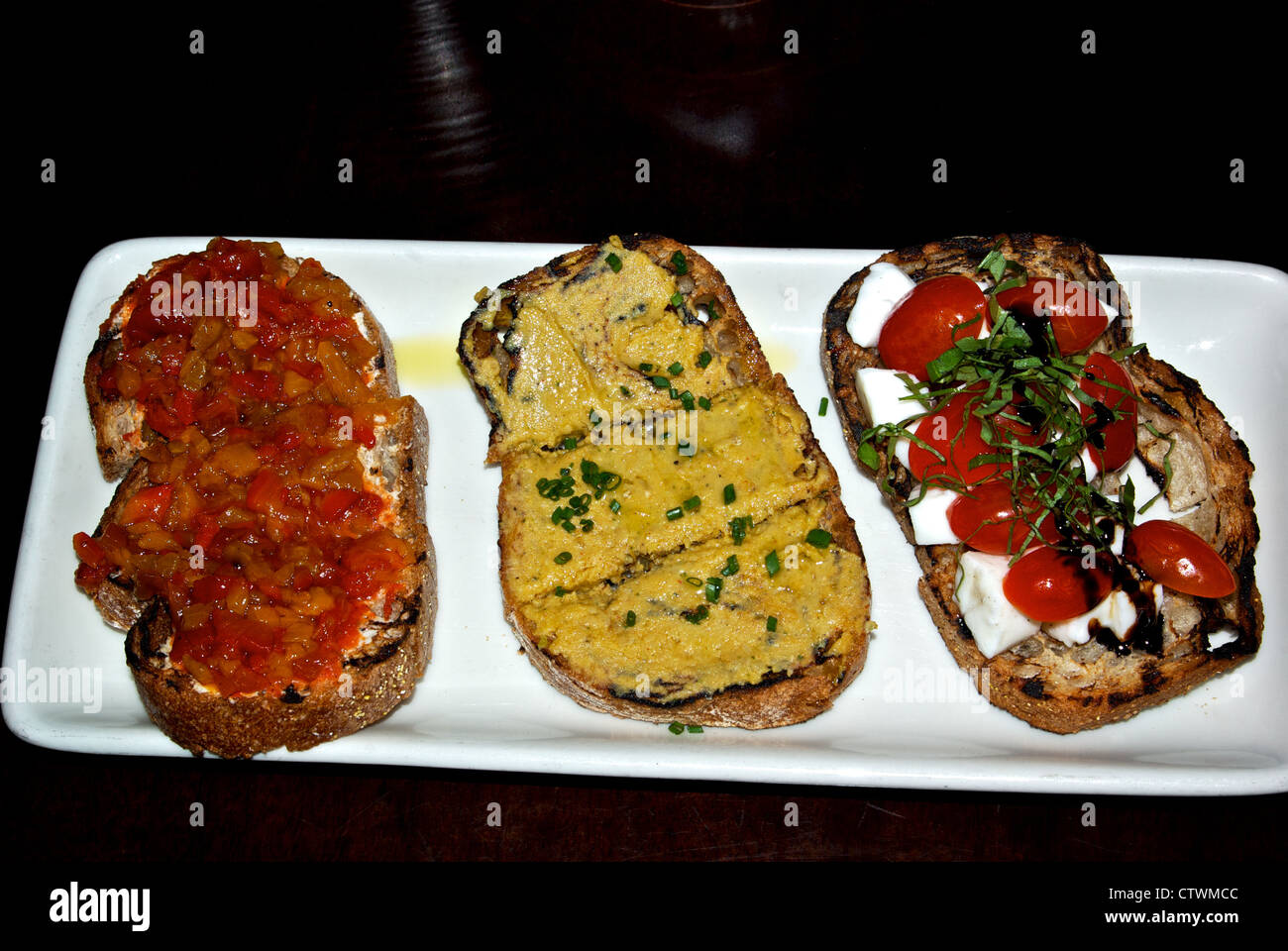 Three bruschettas appetizer tomato onion hummous tomato bocconcini cheese basil basalmic vinegar Stock Photo